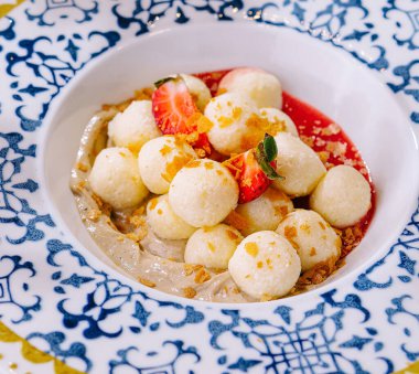 Renkli meyve salatası, kavun topları ve çilek dilimleri. Süslü bir kasede servis ediliyor.