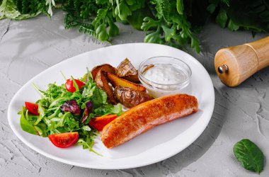 Lezzetli ızgara sosis ve beyaz tabakta ferahlatıcı bahçe salatası.
