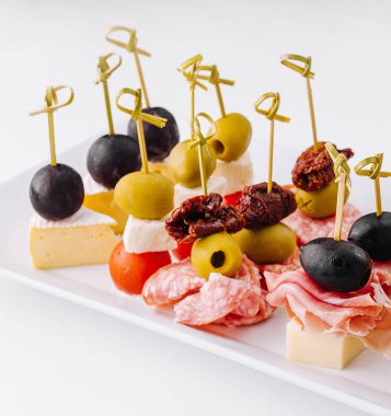 Nefis bir gurme parmak yiyeceği aperatif tabağı ve zarif bir peynir çeşidi. Karides. Zeytin. Salam. Salatalık. Üzüm. Ve kurutulmuş domates. Yemek servisi için mükemmel. Partiler. Ve ziyafetler