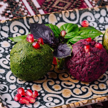 Nar tohumları ve taze fesleğenle süslenmiş, desenli bir tabakta servis edilen nefis vejetaryen aperatifi.