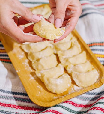 Mutfakta elle hamur şekillendirerek geleneksel ev yapımı pierogi köftelerini hazırlıyorum. El yapımı mutfak lezzetleri için yapılan cila tarifini takip ediyorum.
