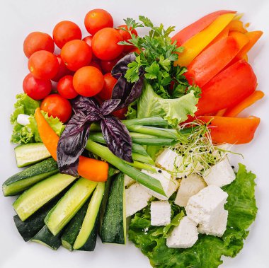 Kare bir tabakta düzgün bir şekilde sıralanmış çiğ sebze çeşitliliğinin üst görüntüsü