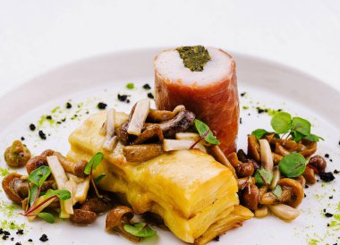 Beyaz tabakta mantarlı ve otlu doldurulmuş tavuğun zarif bir sunumu.