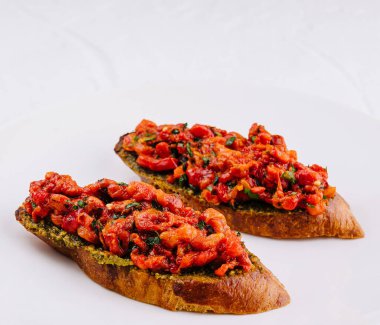 Lezzetli domates ve sebzeli bruschetta ve kızarmış ekmek, temiz beyaz arka planda servis edilir.
