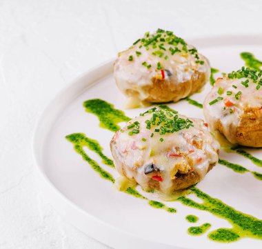 Temiz beyaz bir tabakta servis edilen, taze otlarla süslenmiş, kremalı, zarif mantarlar.