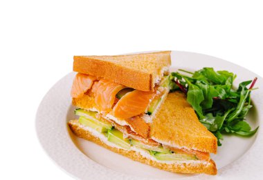 Lezzetli tütsülenmiş somon sandviçi kremalı ve yanında taze, karışık sebzeli.