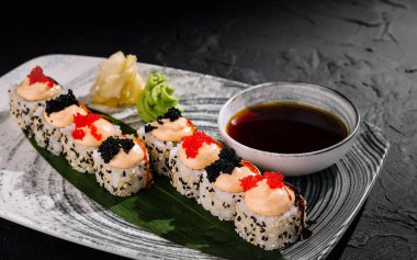 Havyar ve süslerle süslenmiş, soya sosuyla servis edilen zarif suşi ruloları.