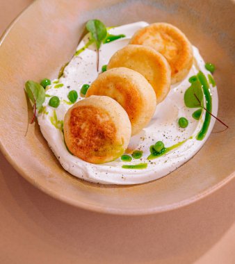 Taze otlarla süslenmiş beyaz soslu bir yatakta nefis mezeler süzme peynirli krepler.