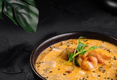 Pirincin yanında bir kasede otlarla süslenmiş lezzetli karides körisi, koyu dokulu arka planda.