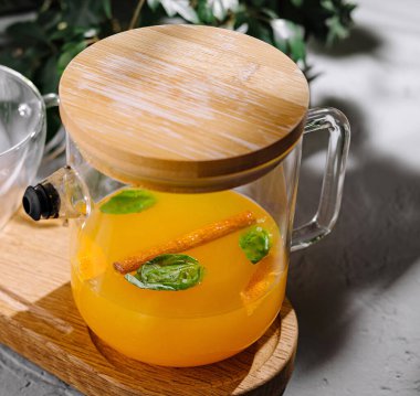 Tahta servis tahtasındaki temiz bir sürahide taze naneli turuncu detoks suyu.