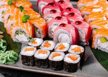 Modern bir tabakta soya soslu ve süslemeli çeşitli dürüm ve sashimi içeren zarif suşi seti.