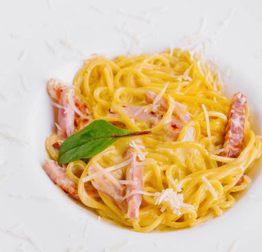 İtalyan spagetti carbonara üstü beyaz tabakta otlarla süslenmiş.