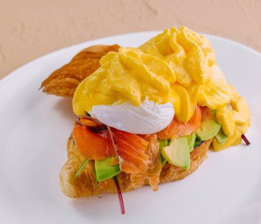 Üzerine füme somon, avokado ve kaymaklı haşlanmış yumurta konmuş lezzetli kruvasan.