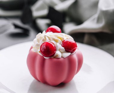 Beyaz tabakta taze böğürtlen ve kremayla süslenmiş pembe krema.