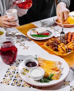Bir masanın yakın plan görüntüsü, arkadaşlarla brunch paylaşımı, içki doldurma ve yemek yeme.