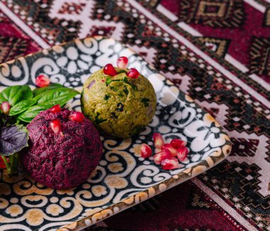 Nar tohumları ve taze fesleğenle süslenmiş, desenli bir tabakta servis edilen nefis vejetaryen aperatifi.