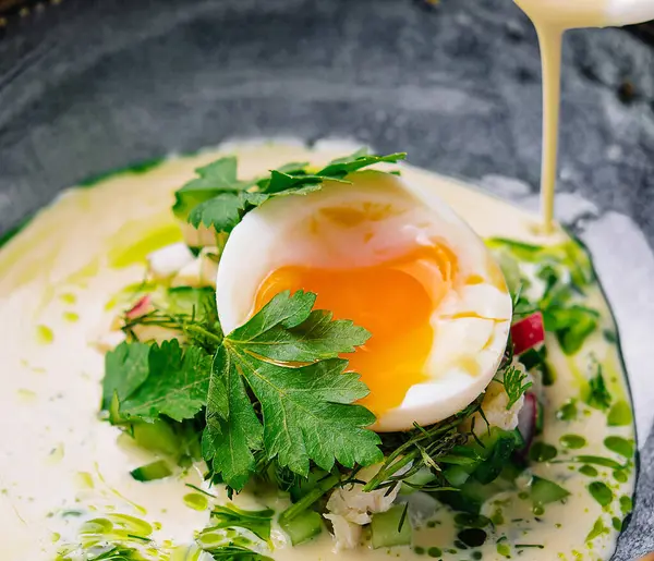 Haşlanmış yumurtadan nefis bir kahvaltı ve taze otlarla süslenmiş Hollandaise sosu.