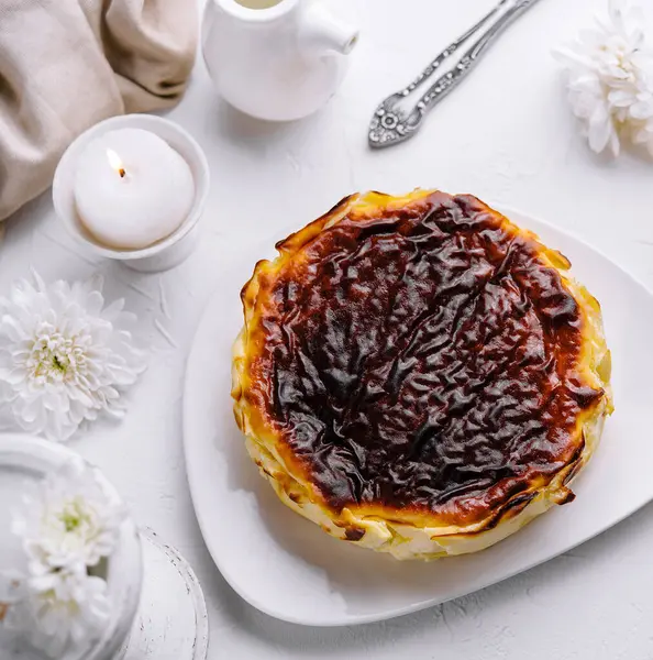stock image Delicioussan sebastian cheesecake with a caramelized top, served on a white plate, surrounded by elegant table decor