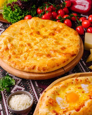 Taze malzemelerle çevrili yumurta ve peynirli pizzayla muhteşem bir Adjarian Khachapuri ziyafeti.