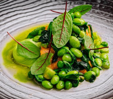 Canlı yeşilliklerle dokulu bir tabakta sunulmuş gurme edamame fasulye salatası