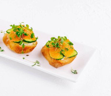 Beyaz tabakta mikro yeşillikler olan zarif somon kanapeleri.