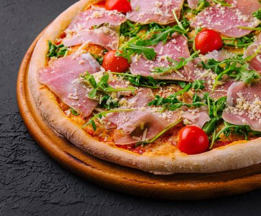 Prosciutto, vişneli domates, roka ve parmesanlı taze pişmiş pizza.