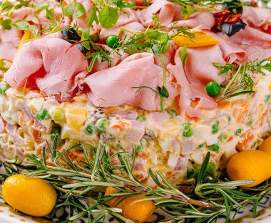 Renkli ve iştah açıcı salata. Beyaz bir arka planda jambon, ot ve kumkatlarla süslenmiş.