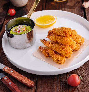 Keskin soslu kızarmış karides, ahşap bir masada taze garnitür.