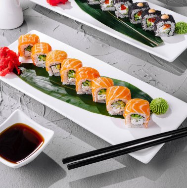 Enfes ve zarif suşi tabağı sunumu geleneksel Japon mutfağını gurme suşi sarmalarıyla sergiliyor. Somon ve ton balığı gibi taze çiğ balıklar. Narin nigiri ve maki. Deniz yosunu. Wasabi.