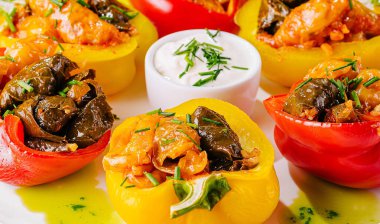 Doldurulmuş dolma dolma dolma dolma biber, otlar ve sosla dolu, beyaz bir arka planda sunulmuş.