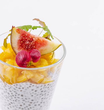 Zarif bir bardak Chia tohumu pudingi olgun incir, turp ve narenciye dilimleriyle süslenmiş.