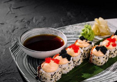 Havyar ve süslerle süslenmiş, soya sosuyla servis edilen zarif suşi ruloları.