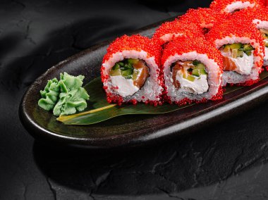 Tarz sahibi kırmızı havyar suşi rulosu zencefil ve wasabi ile servis edilir.