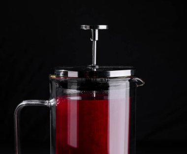 Fransız presi, koyu bir zemine karşı kırmızı meyveli suyla dolu.