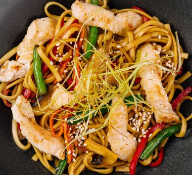 Lezzetli tavuk kızartması, sebzeli şehriye ve siyah tabakta susam.