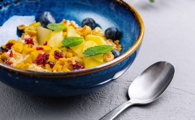 Zarif bir mavi kasede servis edilen naneli süslemeli renkli meyve salatası.