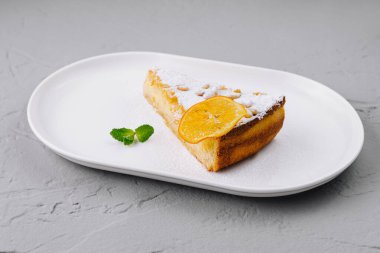 Çekici bir dilim portakallı pasta toz şekerle kaplanmış, bir dilim portakal ve nane ile süslenmiş.