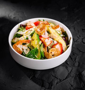 Çilekli lezzetli karides salatası, avokado ve beyaz kasede yeşiller.
