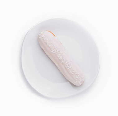 Beyaz arkaplanda izole edilmiş beyaz bir tabakta beyaz kremalı ve hindistan cevizi parçacıkları serpiştirilmiş.