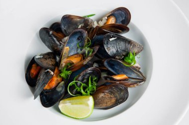 Limon ve taze otlarla süslenmiş sulu midyeler, yemek için hazır.