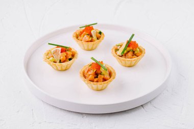 Beyaz bir tabakta sunulan somon, havyar ve otlarla dolu nefis mezeler.