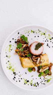 Mantarlı ve otlu sofistike bir tavuk yemeğinin üst görüntüsü, el değmemiş beyaz bir arka planda servis edilir.