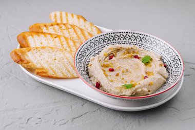 Geleneksel humus, altın tost ekmeği dilimleri ile dekoratif bir tabakta servis edilir.