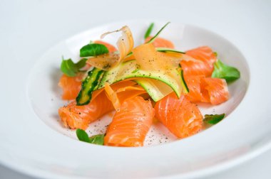 Vibrant dish of smoked salmon and sliced avocado garnished with herbs, served on a white plate