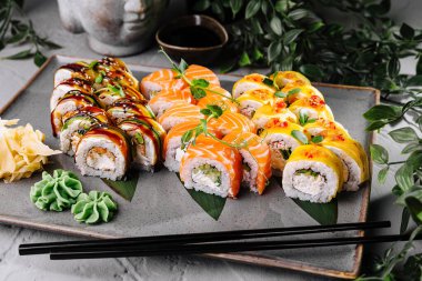Delicious sushi rolls with fresh garnishes served on a modern plate, with soy sauce