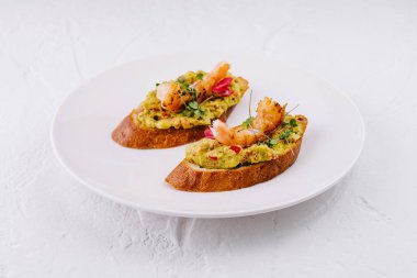 Elegant avocado toast topped with shrimp and edible flowers, served on a sleek white plate