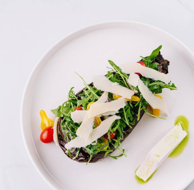 Fırında pişmiş patlıcan, taze yeşillik, peynir ve soslu nefis bir salata tabağı.