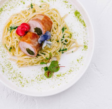 Top view of a delicious stuffed chicken breast on a bed of spaghetti garnished with herbs