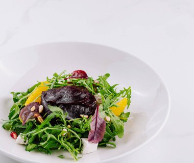 Canlı bir tabak karışık yeşillik, otlar ve beyaz arka planlı narenciye.