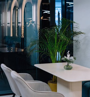 İç mekan bitkilerinin ve modern mobilyaların bulunduğu lüks çalışma alanı.